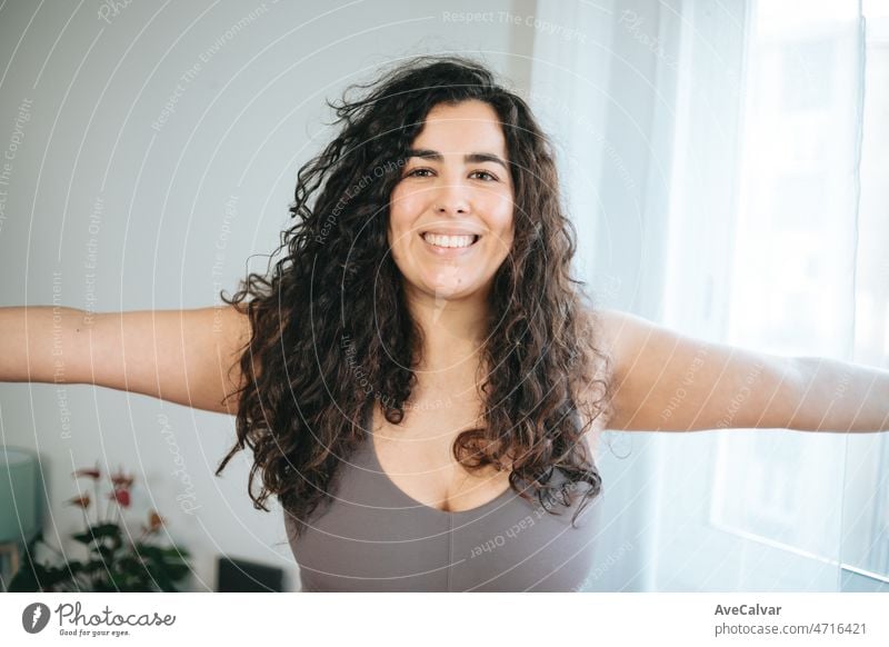 Close up Porträt junge plus size Frau Ausbildung Übung zu Hause, um Gewicht zu verlieren, die Gesundheit. Yoga und Heben zu Hause während des Wochenendes immer bereit für den Sommer. Curly Latina auf sportliche Kleidung