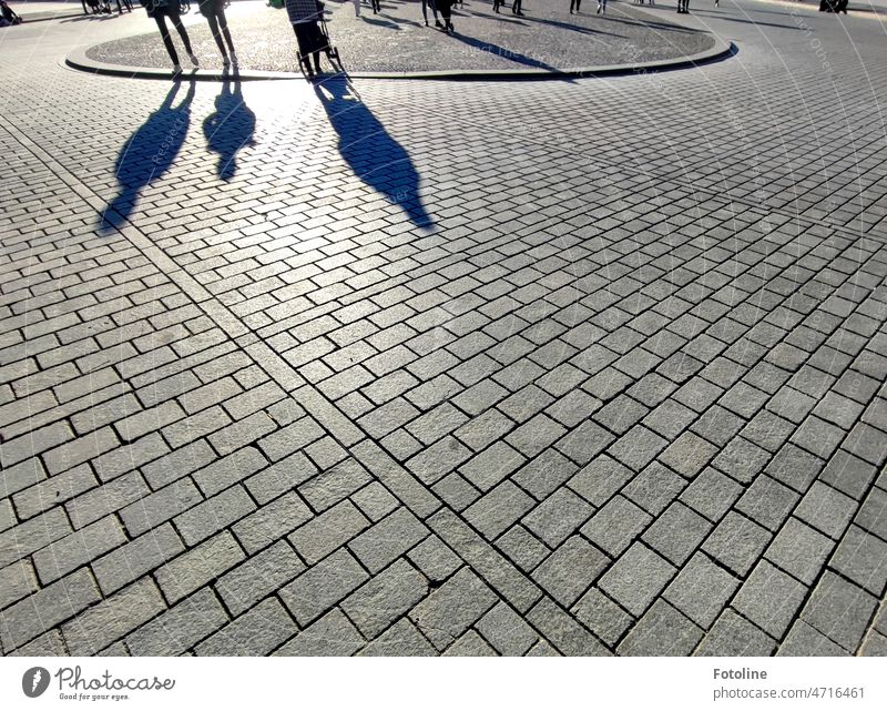 Schattenwelten IV - Auf einem Platz werfen Passanten lange Schatten auf die Pflastersteine Licht Licht & Schatten Sonnenlicht Kontrast Schattenspiel