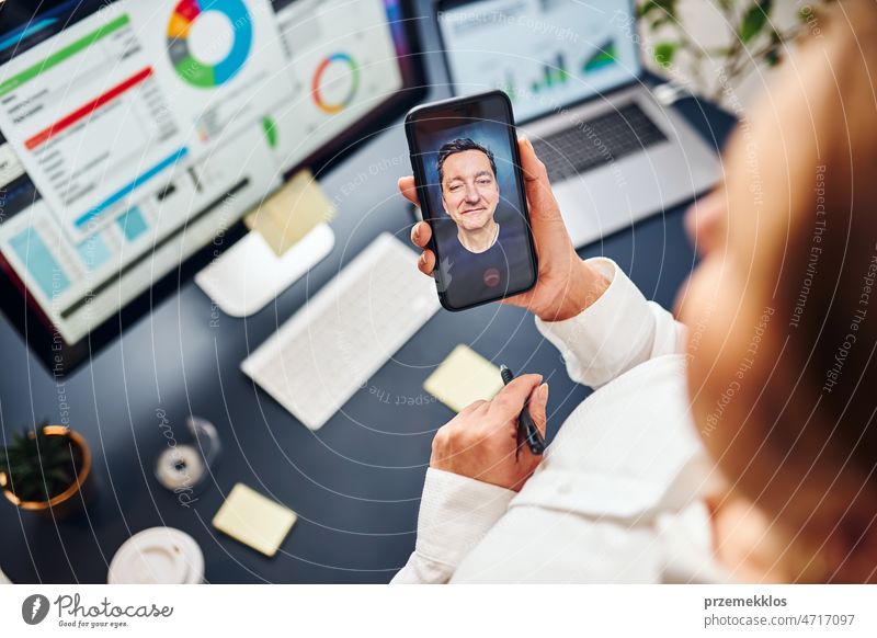 Geschäftsfrau im Videochat auf dem Handy mit ihrem Kollegen. Geschäftsfrau arbeitet mit Daten in Diagrammen, Grafiken und Diagrammen auf dem Computerbildschirm