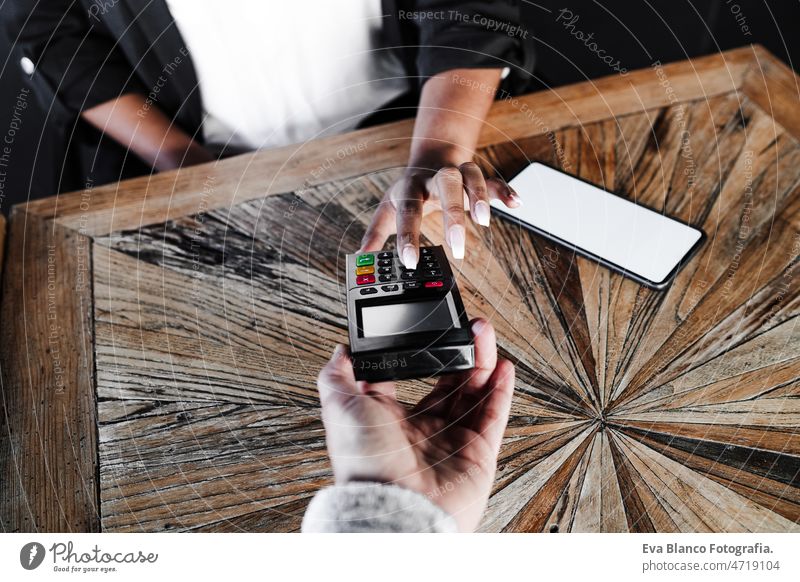 Nahaufnahme einer Frau beim kontaktlosen Bezahlen mit dem Mobiltelefon in einem Cafe. unkenntlich Kontakt weniger Zahlung Handy Technik & Technologie Frauen