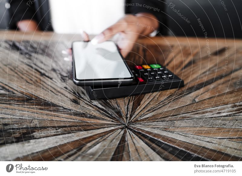 Nahaufnahme einer Frau beim kontaktlosen Bezahlen mit dem Mobiltelefon in einem Cafe. unkenntlich Kontakt weniger Zahlung Handy Technik & Technologie Frauen