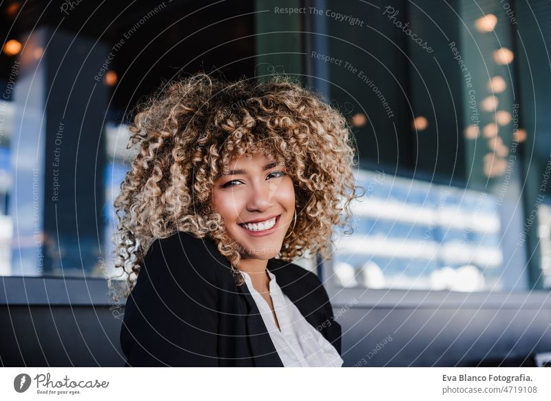 Selbstbewusste hispanische Geschäftsfrau in einem Café, die an einem Laptop und einem Mobiltelefon arbeitet. Technik und Lifestyle Computer Afro-Look Frau