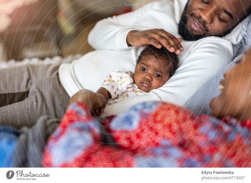 Junge Eltern mit ihrem kleinen Mädchen zu Hause Vater Mutter Kinder neugeboren Familie Mutterschaft echte Menschen im Innenbereich heimwärts flach Appartement