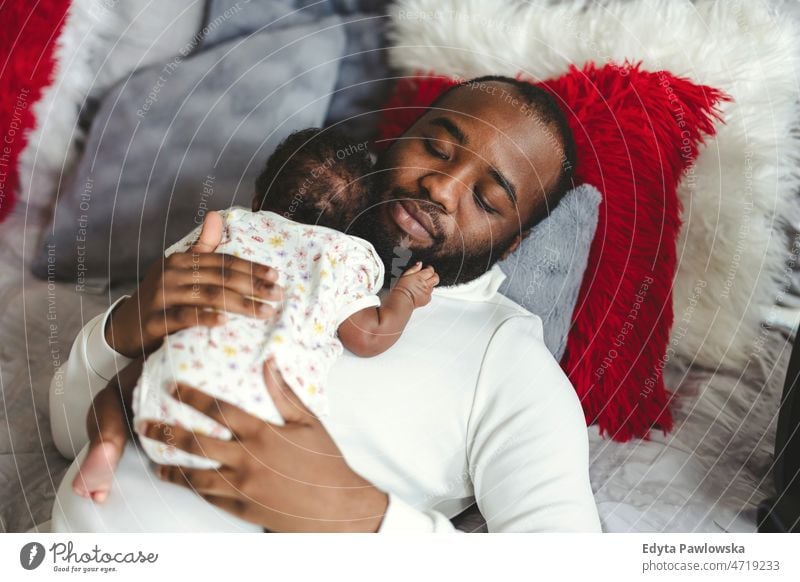 Vater hält sein Baby zu Hause in den Armen Papa Kinder neugeboren Familie Vaterschaft echte Menschen im Innenbereich heimwärts flach Appartement genießen