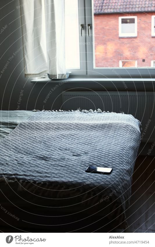 Zimmer mit Fenster und Bett und Mobiltelefon - Gegenlicht vom Fenster - ein ruhiger Raum Schlafzimmer Handy Decke Tagesdecke Ruhe Still Stillleben Heizung