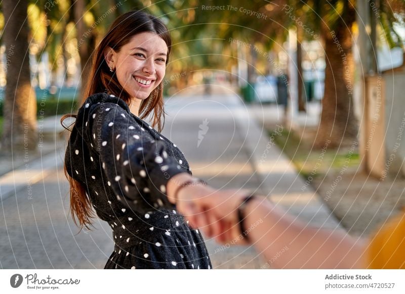 Lächelnde Frau mit "Follow me"-Geste mir folgen gestikulieren Partner romantisch Straße Partnerschaft Liebe feminin Bonden Stil Mode Freizeit heiter Baum Sommer