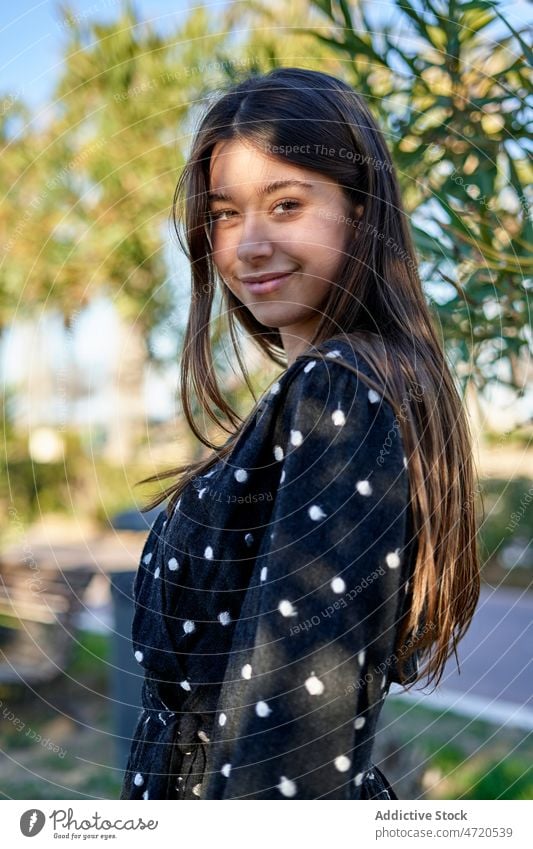 Fröhliche Frau auf sonniger Straße stehend Vorschein Stil feminin Mode Outfit Freizeit Kleidungsstück Bekleidung heiter Baum Sommer jung positiv Optimist Dame