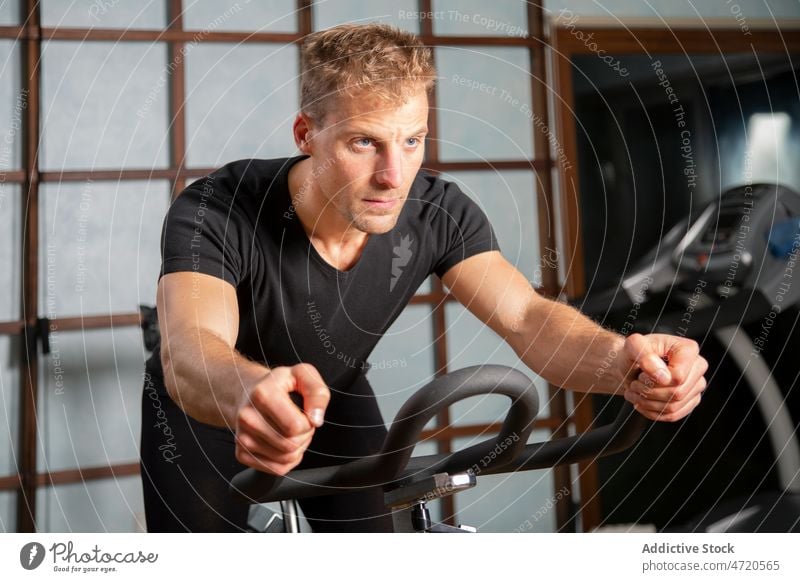 Selbstbewusster Mann, der in einem Fitnessstudio auf einem Radfahrgerät trainiert Sportler Zyklus Maschine Übung Training Bestimmen Sie selbstbewusst passen