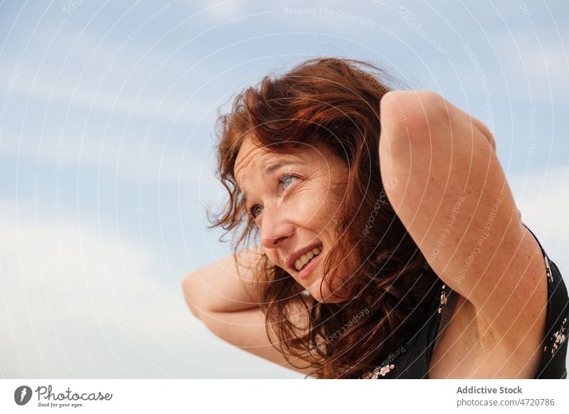 Frau mit den Händen auf dem Kopf schaut weg Vorschein feminin Stil Natur Harmonie friedlich verträumt Haare berühren Sommer Himmel wolkig Sonnenkleid Windstille