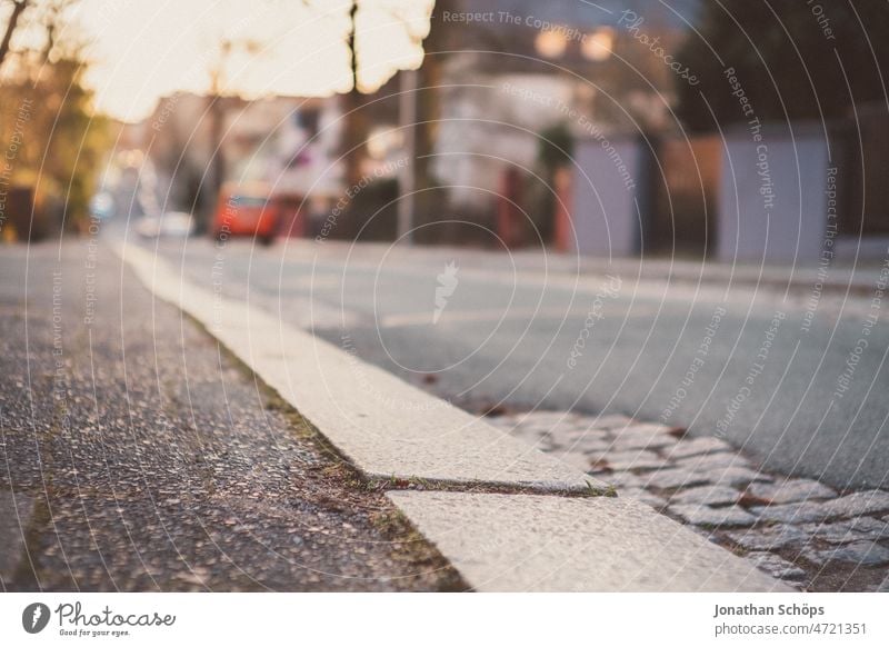 Bordsteinkante auf einer Straße bei Abendsonne Fußweg Gehweg sonnig Winter Straßenrand Straßenbelag urban leer Asphalt Kopfsteinpflaster Flickenteppich vintage