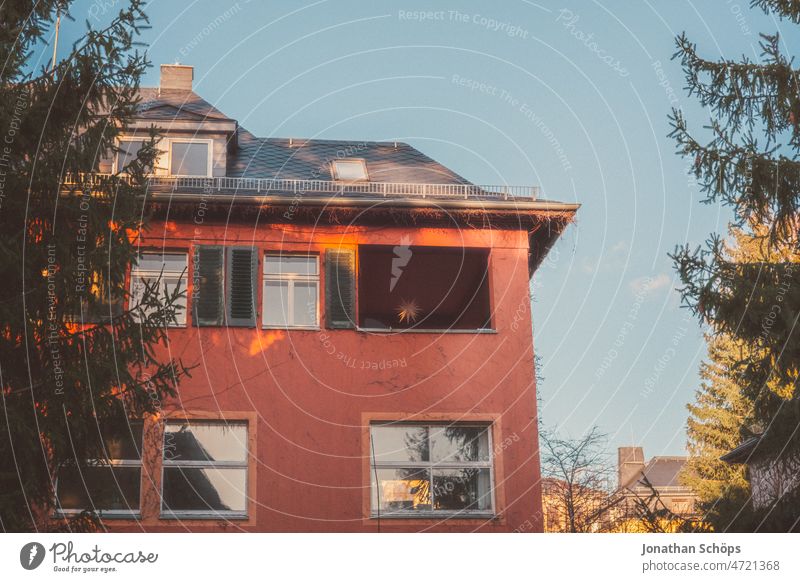 rote Fassade Altbau Haus im Abendlicht Fensterladen Fensterläden Schatten Mehrfamilienhaus Eigenheim Stadtrand wohnen alt Miete Bäume warmes Licht abends