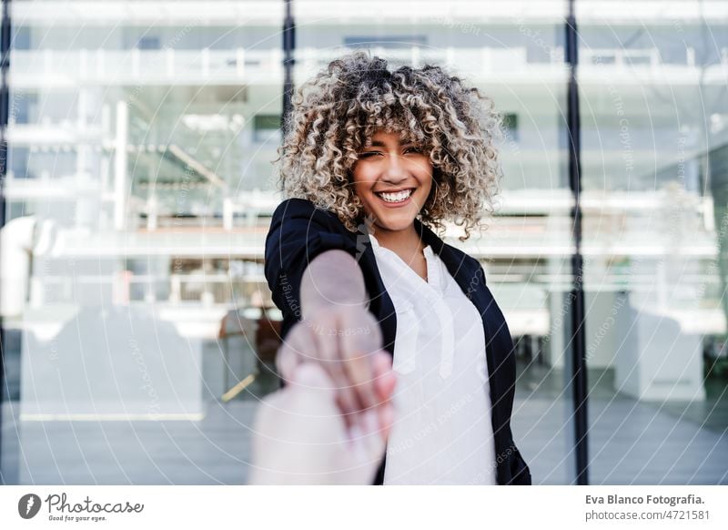 schöne lachende Geschäftsfrau in der Stadt hält Hand mit Freund. Gebäude Hintergrund Glück Händchen haltend Großstadt Lachen Freunde Afro-Look hispanisch Handy