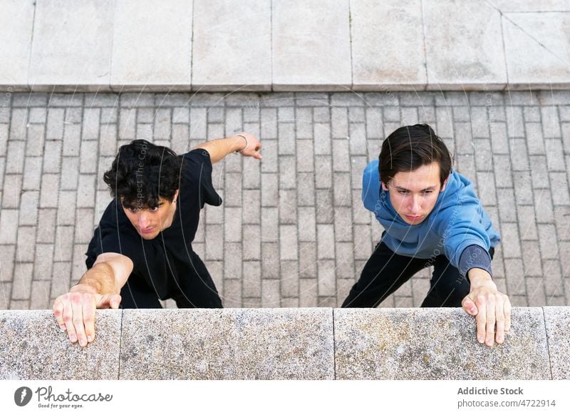 Männer halten die Hand an die Wand und hängen Training Straße passen Halt Athlet Händchen haltend Großstadt männlich Typ Le Parkour Übung springen Fitness Borte