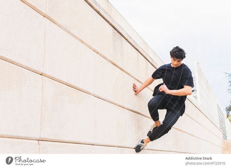 Sportlicher Mann macht Parkour-Stunt an der Wand auf der Straße Le Parkour springen Gebäude über der Erde akrobatisch Energie ausführen Typ männlich Trick