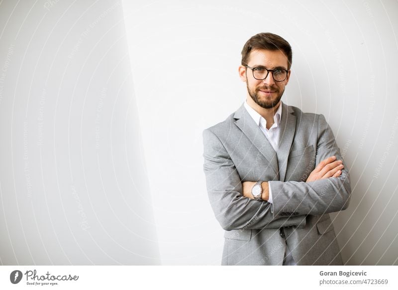 Junger moderner Geschäftsmann an der Wand im Büro stehend Vollbart Business Unternehmen korporativ Mitarbeiter Brille finanziell gutaussehend im Innenbereich