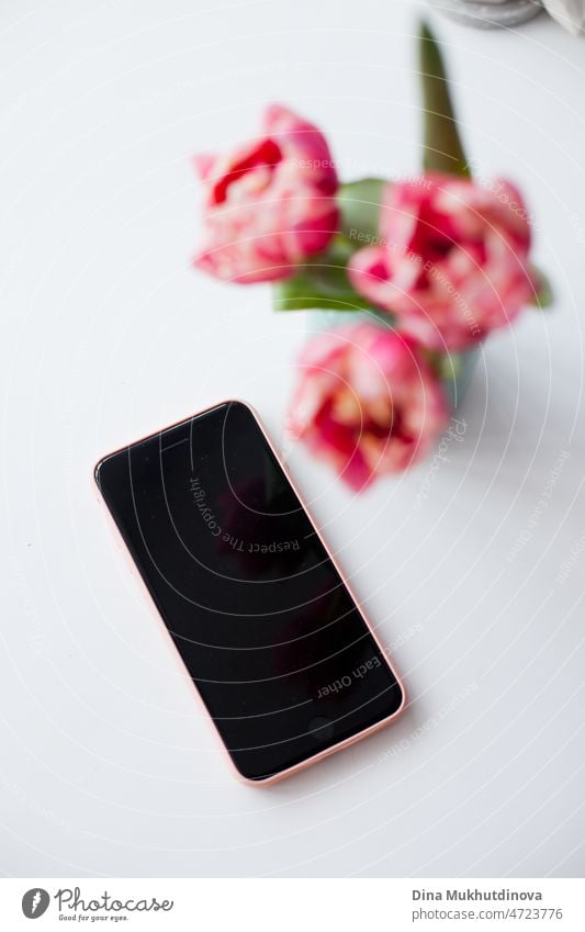 Handy und drei rosa Tulpen in einer kleinen Vase auf weißem Hintergrund, Smartphone und Home Decor Frühling Hintergrund mit Blumen Telefon Technik & Technologie