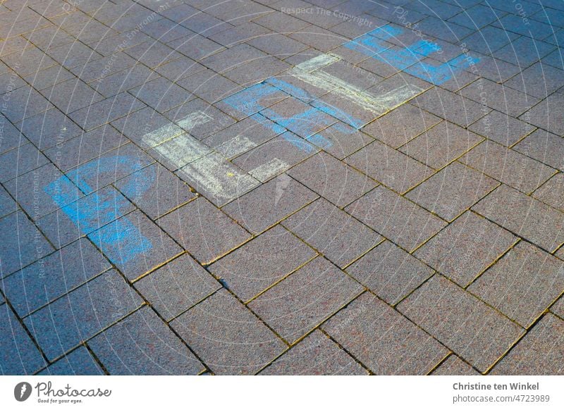 PEACE steht in blau und gelb mit Strassenmalkreide geschrieben auf den Pflastersteinen in der Fussgängerzone Hoffnung auf Frieden Friedensangebot Peace