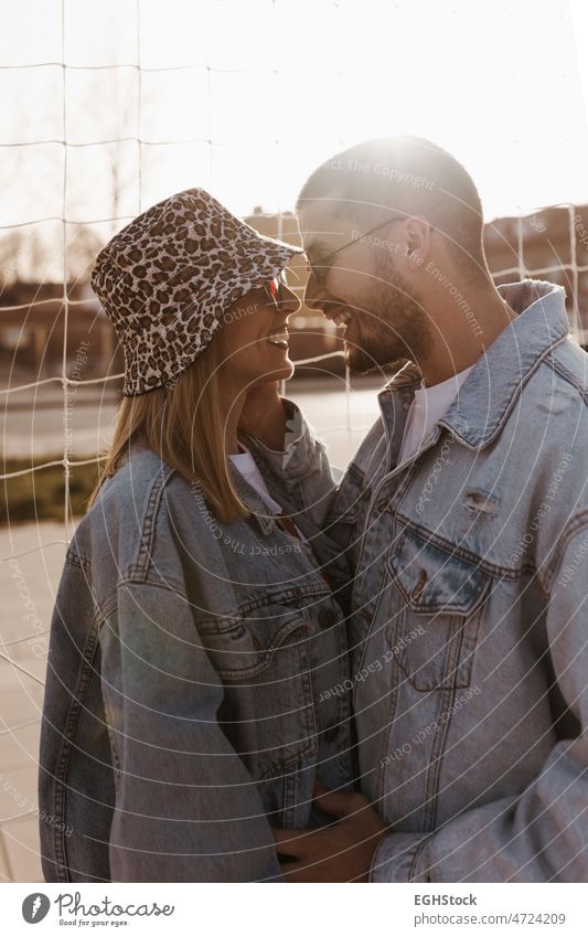 Freundin und Freund in den Zaun schauen sich gegenseitig und lachen. Glückliches Paar. Lachen berührend Hände Frau Mann Liebe Zusammensein jung Partnerschaft