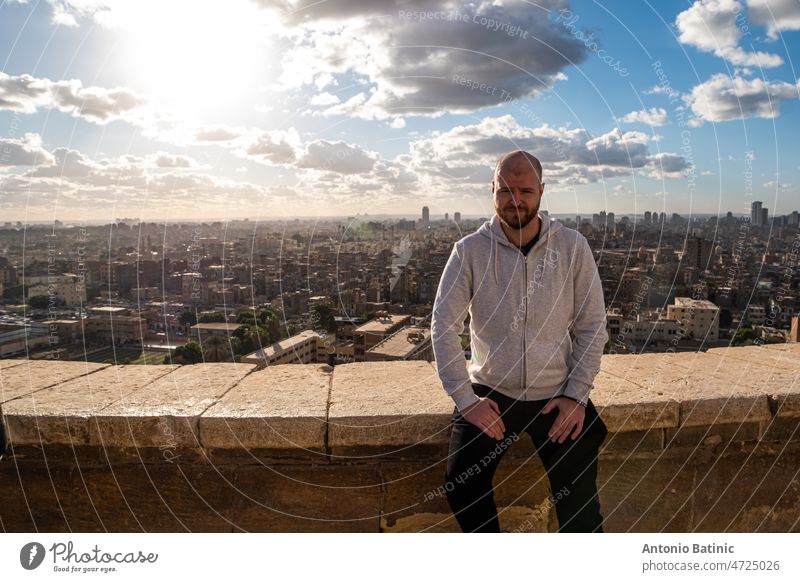 Mann sitzt auf einem Felsvorsprung in Kairo, Blick auf die Stadt und die Pyramiden in der Ferne reisen Ägypten Luxor antik Gizeh Architektur Landschaft