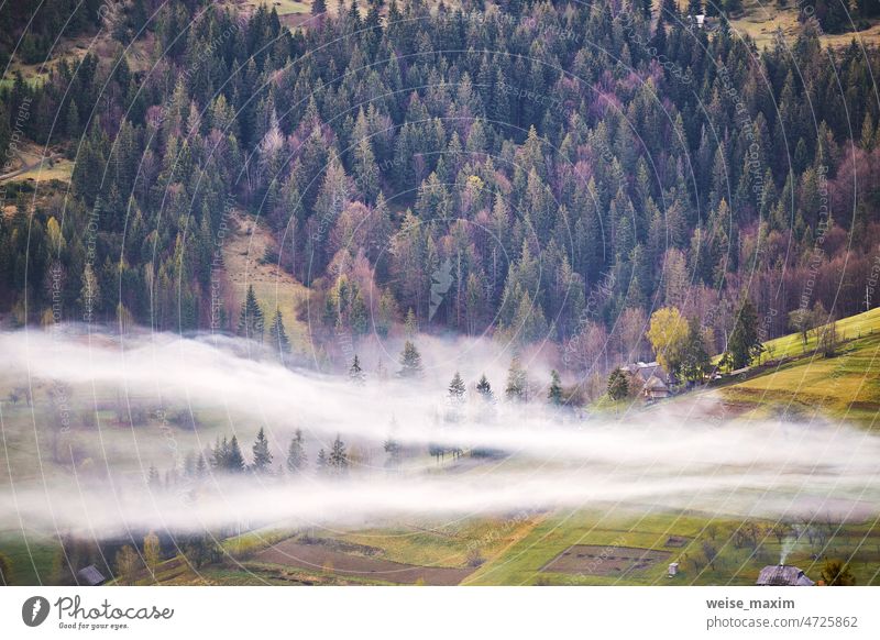 Schöne Frühlingslandschaft. Traditionelle Bergdorf auf den Hügeln. Ländliche Ukraine Karpaten Sonnenaufgang. Rauch aus dem Haus. Nebelwolken Berge u. Gebirge