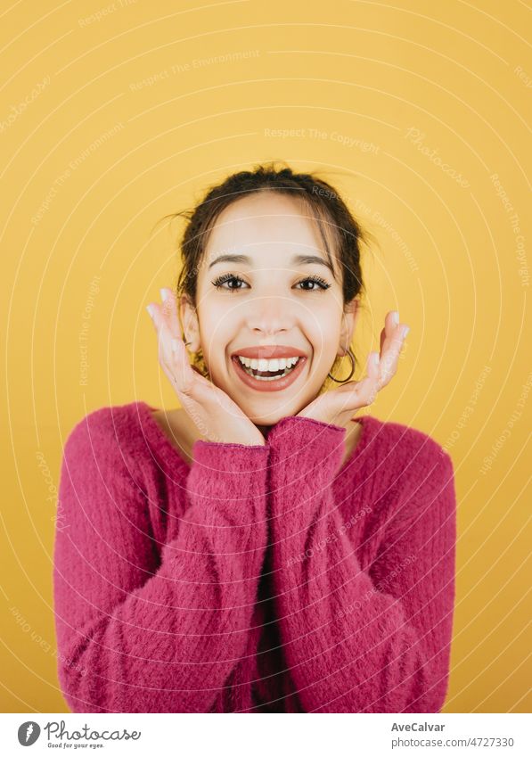 Junge Frau auf rosa lächelnd während berühren Gesicht zur Kamera. Junge Frau Haltung. Gelber Ton Farbe Hintergrund, Ausdruck der normalen Menschen. Mockup-Konzept mit Menschen