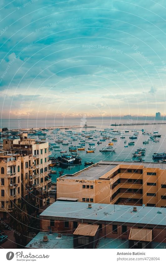 Vertikale Aufnahme der Bucht von Alexandria, erstaunliche goldene Stunde bei Sonnenaufgang. Blick von einem hohen Wohnhaus auf die Umgebung, so viele Fischerboote im Hafen verankert