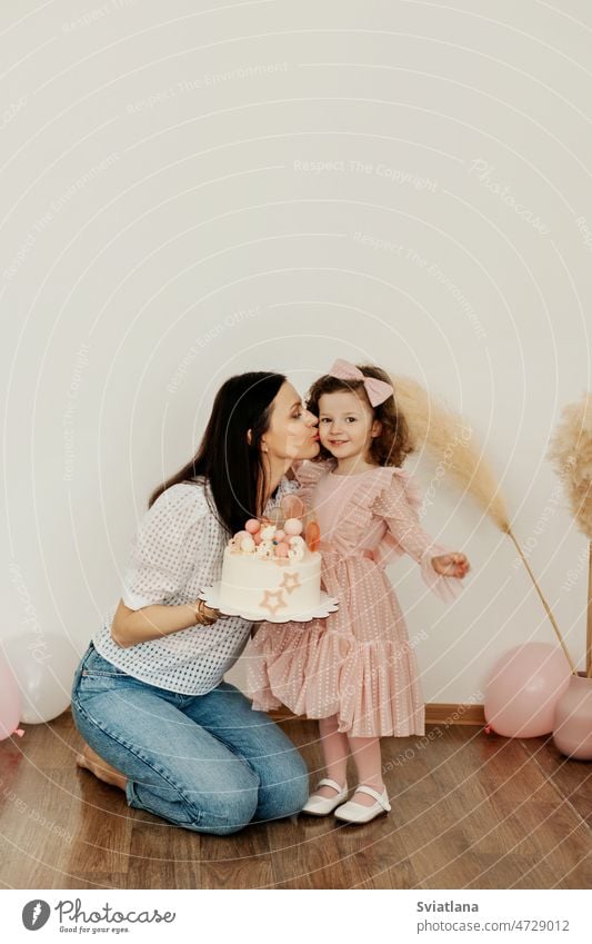 Eine junge Mutter schenkt ihrer bezaubernden Tochter eine Geburtstagstorte. Kuchen Mama Bälle Baby wenig Fröhlichkeit Überraschung Kind Hintergrund Glück Feier