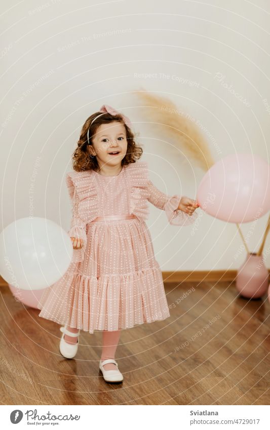 Ein charmantes kleines Mädchen mit Luftballons an ihrem Geburtstag hat Spaß und lacht Baby Kleid Bälle niedlich wenig Lächeln rosa schön Glück süß Lachen Licht