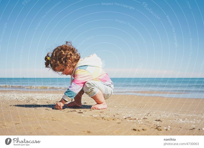 Großansicht eines kleinen Mädchens mit Regenbogen-Kapuzenpulli beim Spielen am Strand Freiheit Fröhlichkeit Feiertage Baby Kleinkind Familie frei MEER Ufer