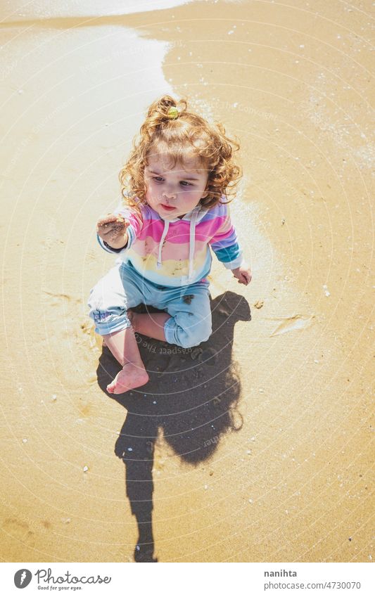 Mittelteil eines kleinen Mädchens beim Spielen am Meer Porträt Baby bezaubernd Strand Sommer lockig Behaarung Freude genießen Kleinkind Regenbogen Süßer