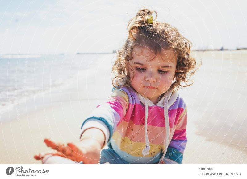 Mittelteil eines kleinen Mädchens beim Spielen am Meer Porträt Baby bezaubernd Strand Sommer lockig Behaarung Freude genießen Kleinkind Regenbogen Süßer