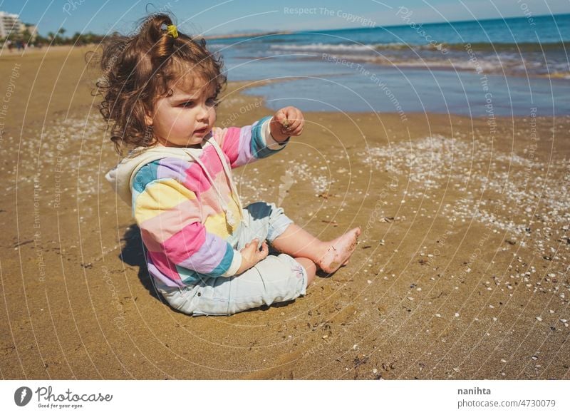 Mittelteil eines kleinen Mädchens beim Spielen am Meer Porträt Baby bezaubernd Strand Sommer lockig Behaarung Freude genießen Kleinkind Regenbogen Süßer