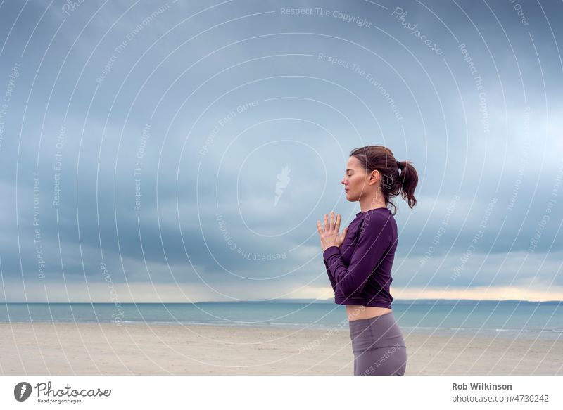 Abgeschnittene Ansicht von Frau stehend meditieren und üben Yoga am Meer. Fitness und geistige Gesundheit Konzept. Erwachsener attraktiv Strand Cloud