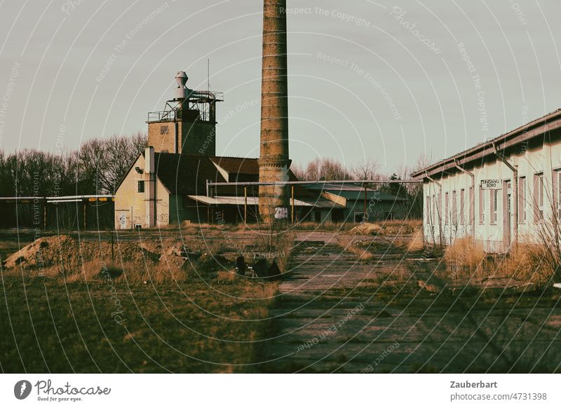 Verlassene Fabrik, Schornstein, Bürogebäude und Vorplatz mit Betonplatten im Abendlicht verlassen lost places alt kaputt Vergänglichkeit verfallen