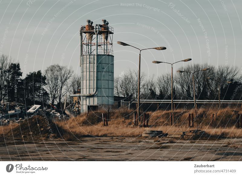 Verlassene Fabrik, Silobehälter, Straßenlaternen, Vorplatz mit Beton, Müllhaufen verlassen lost places Abend Abendlicht alt kaputt Vergänglichkeit verfallen