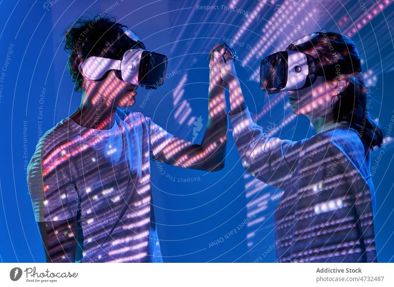 Pärchen erkundet den Cyberspace unter glühenden Lichtern Paar VR Virtuelle Realität Headset Zukunft Metaversum interaktiv Technik & Technologie erkunden