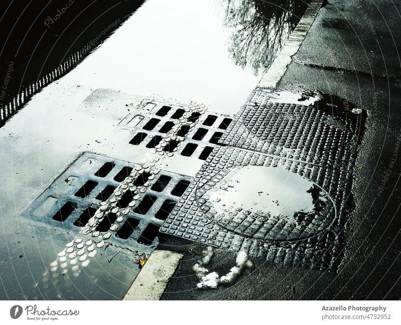 Wasser fließt in den Kanalisationsschacht. Nasse Straße mit Kanalisationsschächten. abstrakt Asphalt Allee Hintergrund helles Sonnenlicht kreisen Großstadt