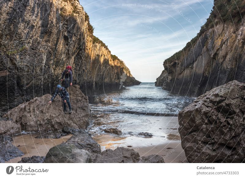 Felsen am Strand und zwei kraxelnde Männer Tag Tageslicht nass Urelemente Ferien & Urlaub & Reisen Küste Wasser Himmel Wolken Horizont Meer Klippen Landschaft