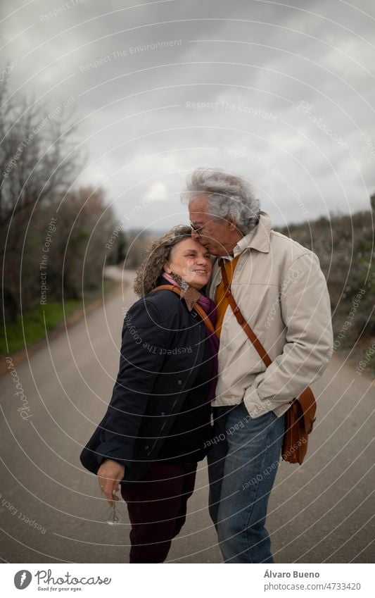 Ein Paar, Mann und Frau, 60 und 70 Jahre alt, mit grauen Haaren, zeigen ihre Zuneigung mit einem Kuss während eines romantischen Frühlingsspaziergangs in einer ländlichen Gegend in der Provinz Zaragoza, Aragon, Spanien