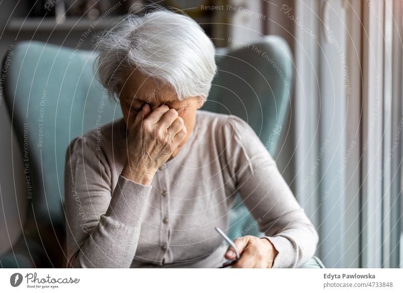 Ältere Frau leidet unter Kopfschmerzen allein zu Hause häusliches Leben älter Oma Großmutter graue Haare heimwärts im Innenbereich Lifestyle reif alt