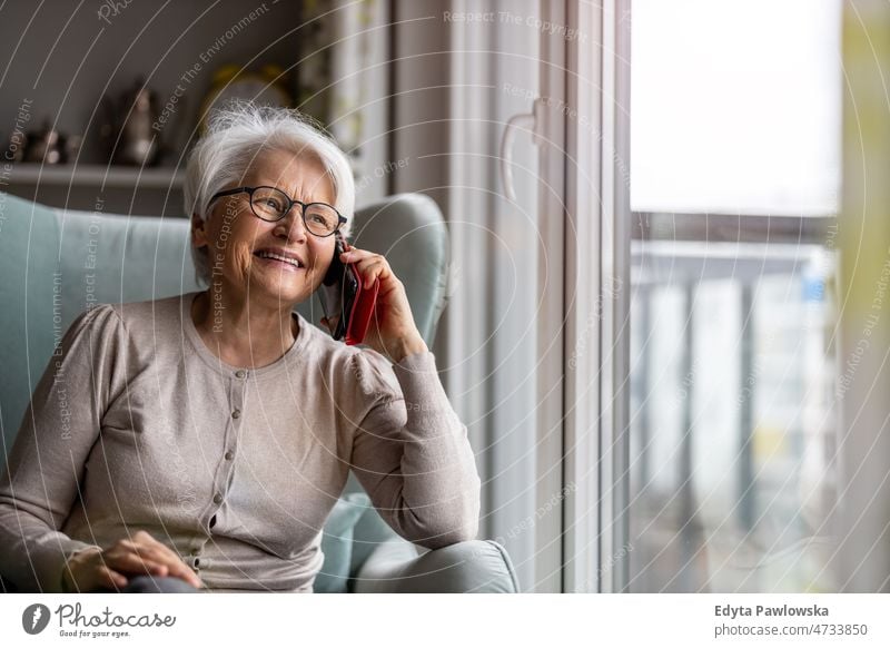 Ältere Frau benutzt Mobiltelefon zu Hause Brille allein häusliches Leben älter Oma Großmutter graue Haare heimwärts im Innenbereich Lifestyle reif alt