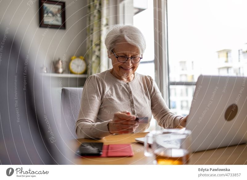 Ältere Frau beim Online-Shopping am Laptop zu Hause Brille allein häusliches Leben älter Oma Großmutter graue Haare heimwärts im Innenbereich Lifestyle reif alt