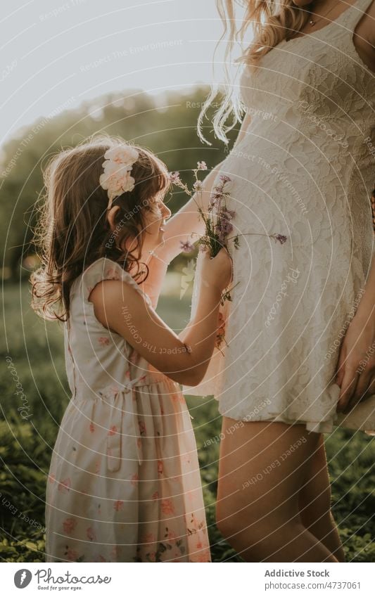 Crop schwangere Frau und Tochter mit Blumenstrauß im Sommer Natur Mutter Mädchen Schwangerschaft Kind Mama Zuneigung warten Zusammensein Park Glück Bonden