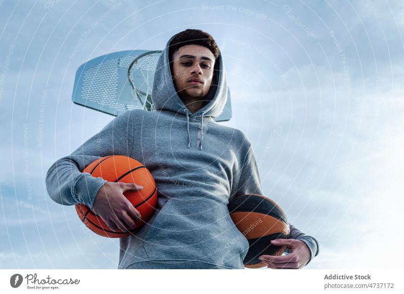 Hispanischer Mann mit Bällen in der Nähe des Basketballkorbs Sportler Sportpark Training Spiel Gesunder Lebensstil Gericht Hobby Reifen Ball Spielplatz