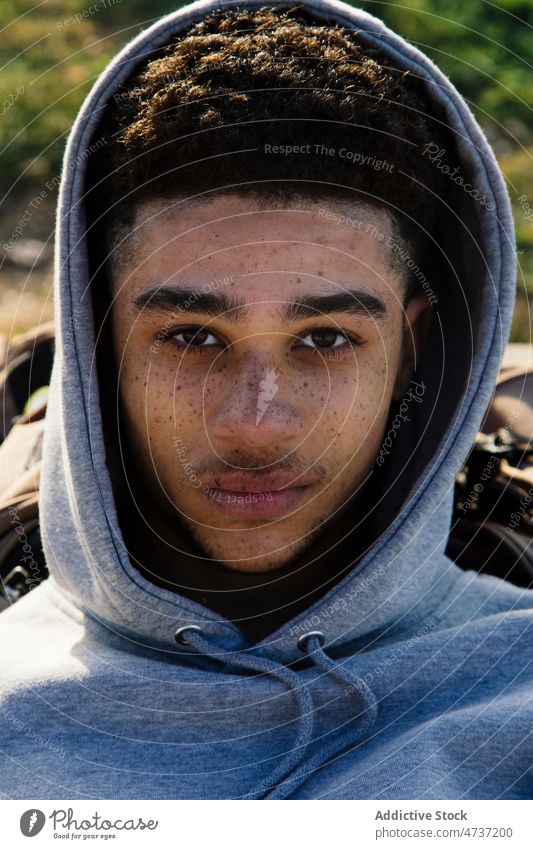 Hispanischer Mann im Kapuzenpulli auf der Straße Vorschein Großstadt lässig Streetstyle Stil informell Jugend männlich ernst Windstille jung dunkles Haar