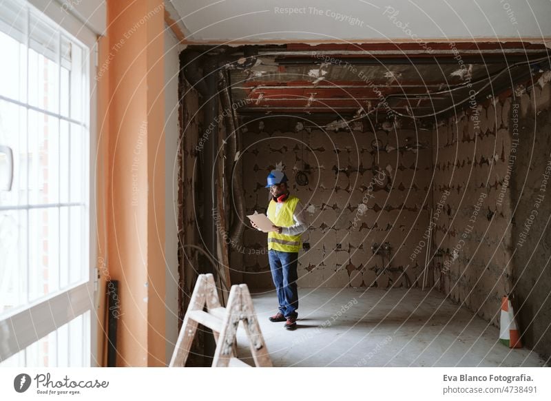 Vorarbeiter oder unkenntlicher Architekt bei der Arbeit an Bauplänen auf der Baustelle. Heimwerken Haus Polier Blaupausen professionell Isolierung Ohrenschützer