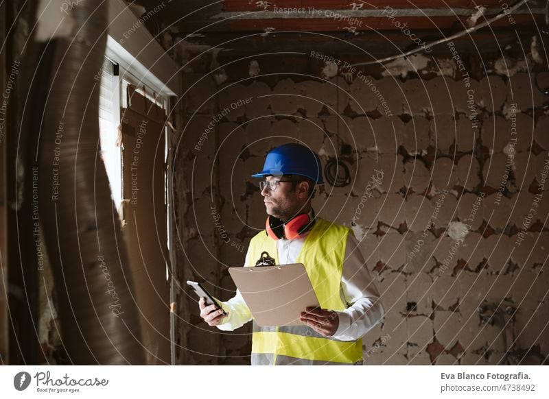 Vorarbeiter oder unkenntlicher Architekt bei der Arbeit an Bauplänen auf der Baustelle. Heimwerken Haus Polier Blaupausen professionell Isolierung Ohrenschützer