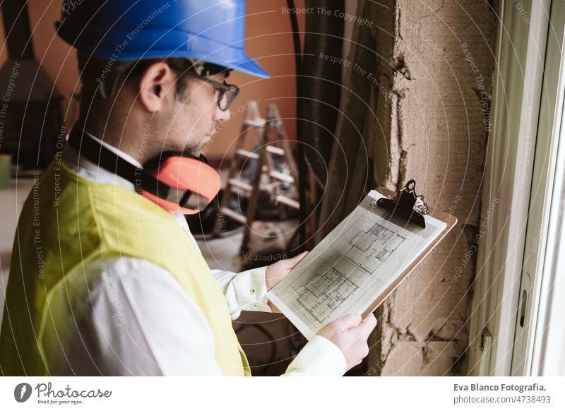 Vorarbeiter oder unkenntlicher Architekt bei der Arbeit an Bauplänen auf der Baustelle. Heimwerken Haus Polier Blaupausen professionell Isolierung Ohrenschützer