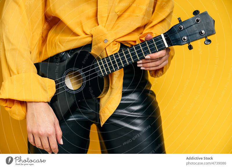 Stilvolle Frau stehend mit Ukulele im Studio Musiker akustisch Hobby Instrument üben kreieren redaktionell kreativ Schnur Melodie Atelier Fähigkeit Talent