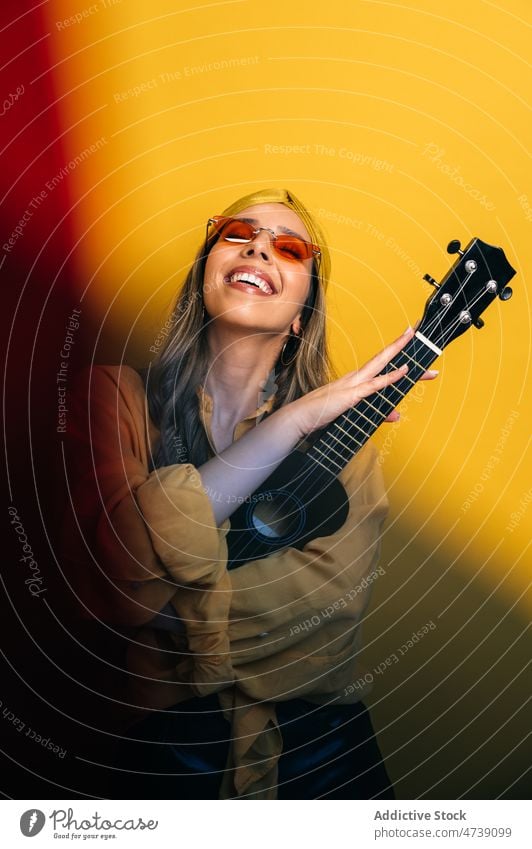 Frau mit Ukulele in hellem Studio Spieler Pause Musik Instrument Stil Hobby cool Tierhaut redaktionell Model Musiker akustisch lange Haare üben Künstler Dame